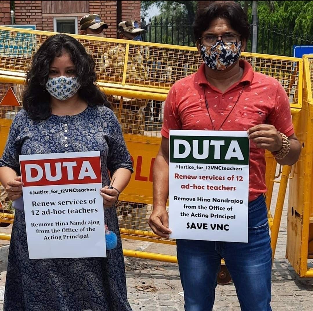 Two teachers hold DUTA placards demanding renewed services for ad hoc teachers